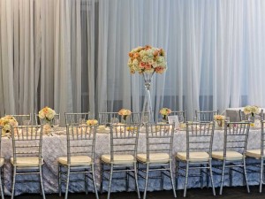 Gorgeous White Linens, Silver Bamboo Chairs, perimeter pipe and drape with Aqua Uplighting room setup at the Red Oak Ballroom in Houston, CityCentre