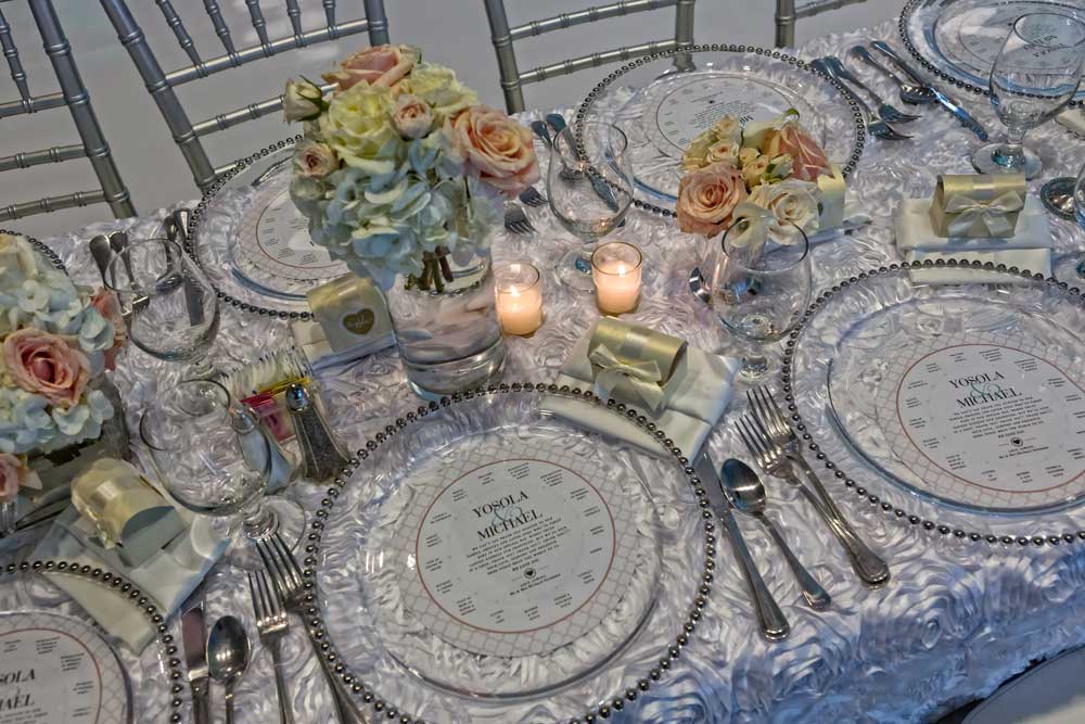 Gorgeous Textured White Linens, Silver Bamboo Chairs, and Silver-rimmed Plate Chargers Wedding Party Table setup at the Red Oak Ballroom in Houston, CityCentre