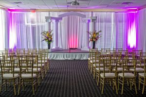 Live Oak Room at Red Oak Ballroom Austin is set for a Wedding Ceremony, perimeter drape, chivari chairs, small stage with columns