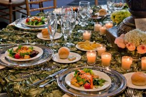 Ornate green Table Overlays with silver rimmed plate chargers, preset salads and gorgeous centerpieces at Red Oak Ballroom, Houston CityCentre